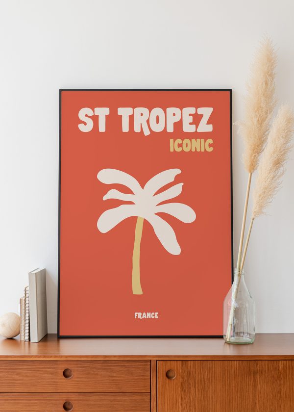 Affiche déco Saint-Tropez Iconic avec palmier blanc et tronc ocre sur fond rouge orangé, encadrée sur meuble en bois.